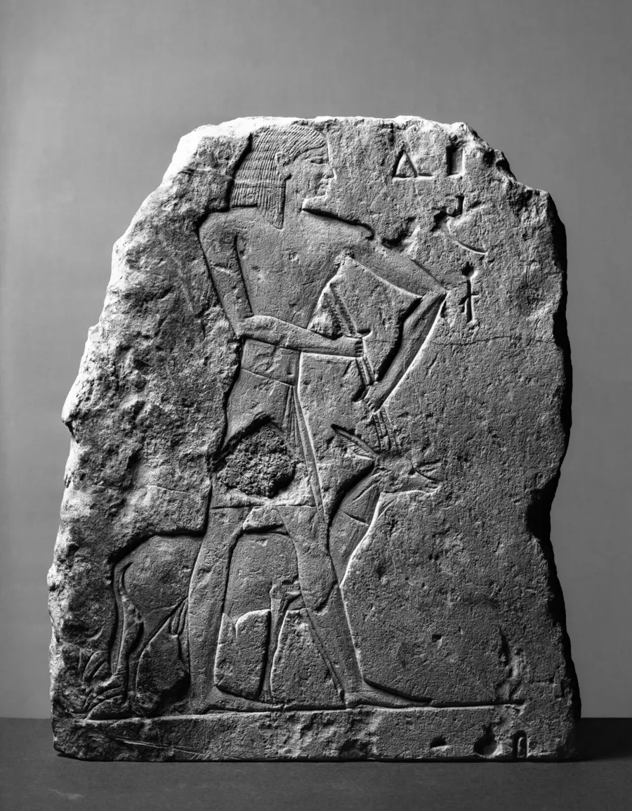 Fragment of an Egyptian stone tomb relief: an attendant holds an oryx by its horns